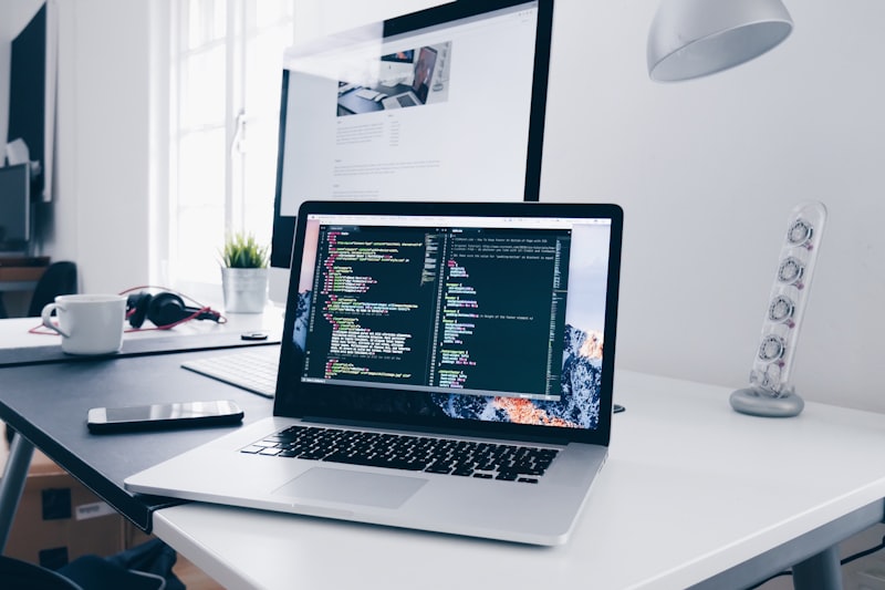 MacBook laptop flat lay on a white desk showing backend code
